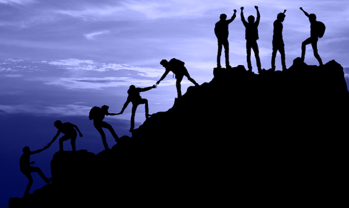 Nine individuals hiking to the top of a summit, some reaching back to help one another and some at the summit, raising arms in the air for achievement