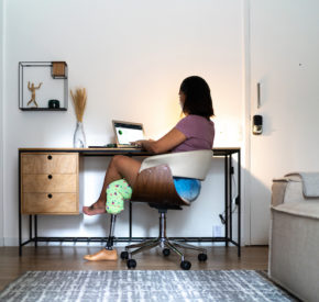 User with a prosthetic right leg using a laptop at a desk at home