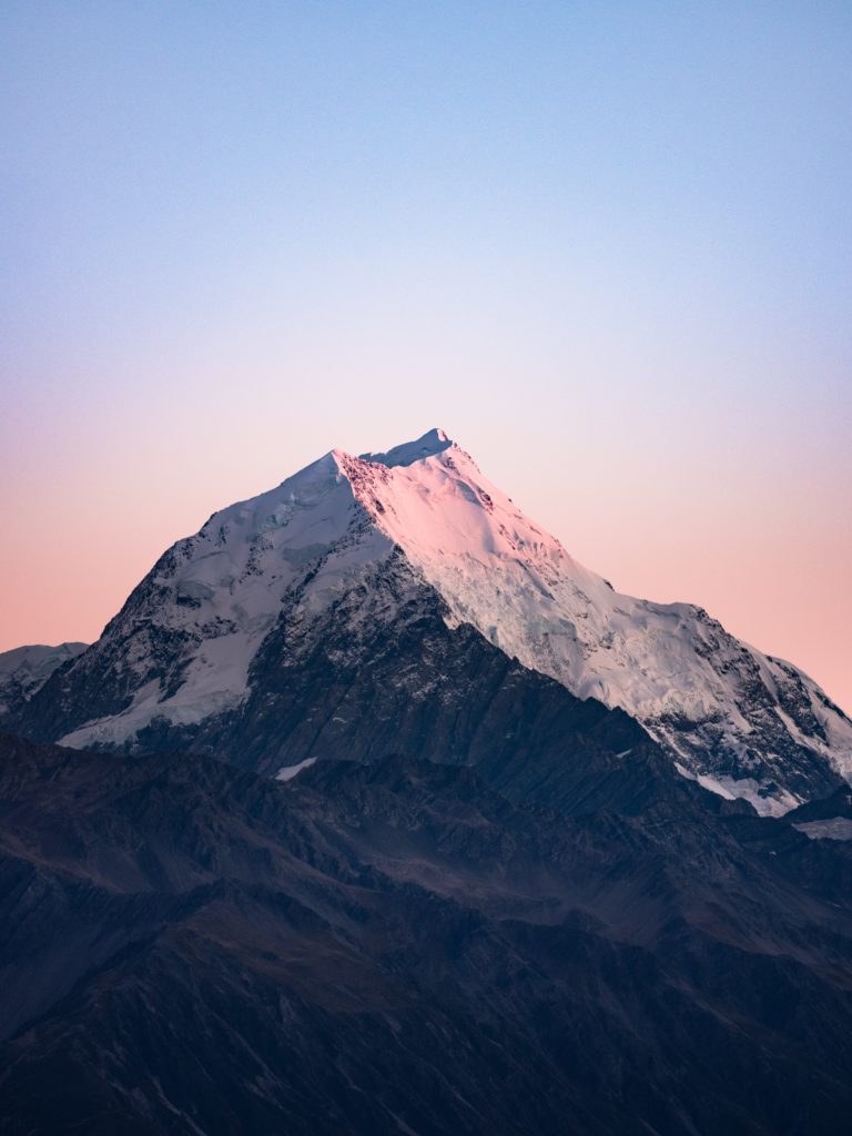 Snowcapped mountain at sunrise with blue sky above