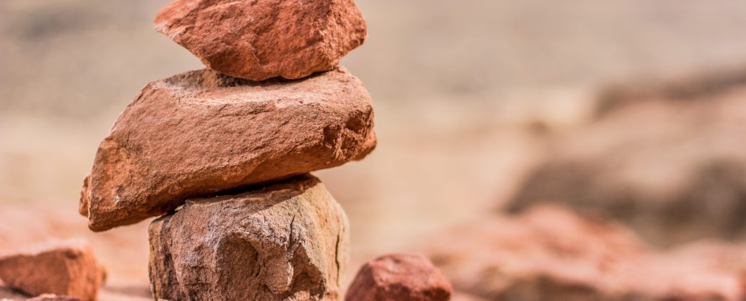 Three red-hued stacked and balanced rocks of various sizes for a meditative effect