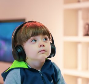young child with headphones gazing up at an angle