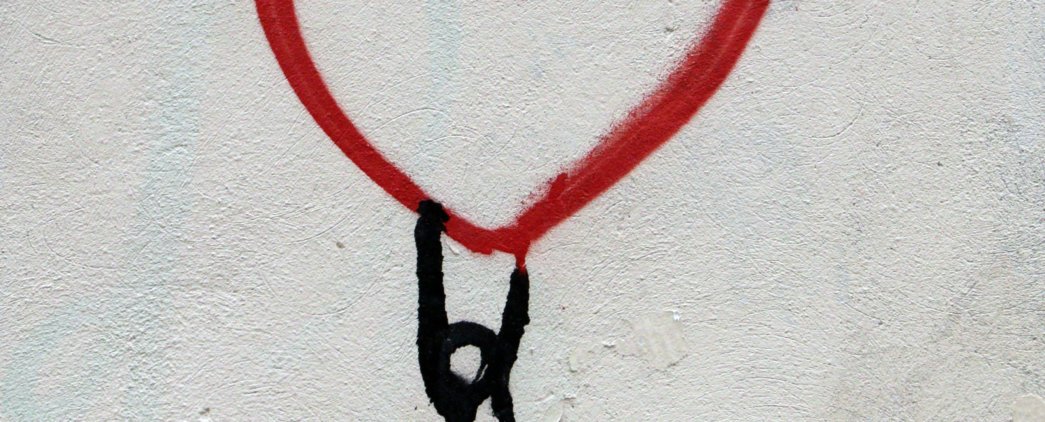 Stick figure hanging on or lifting up the bottom of a red line drawing of a heart