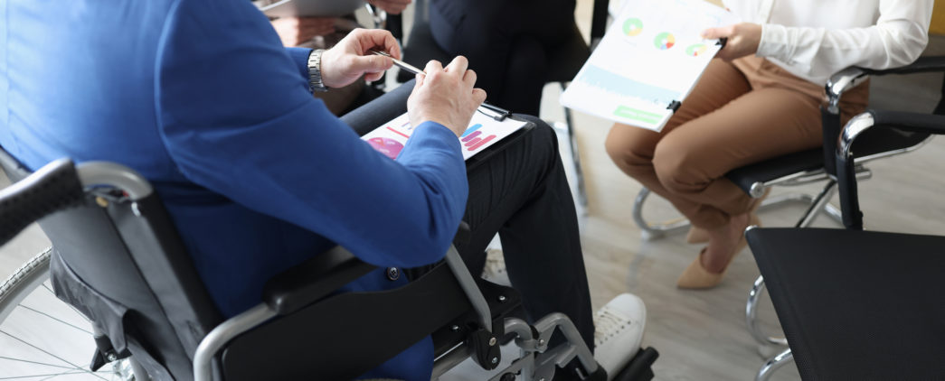 A man in a wheelchair attends a meeting.