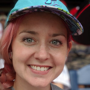 smiling headshot of Liza Grant with blue Phillies baseball cap and pink braided hair
