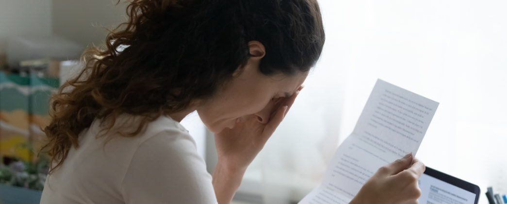 A distressed woman reads a rejection letter.