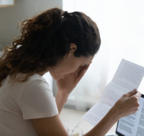 A distressed woman reads a rejection letter.