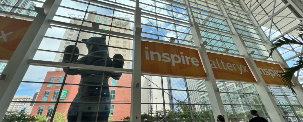 Atrium at the 2022 Alteryx Inspire conference, featuring two attendees and a large bear statue.