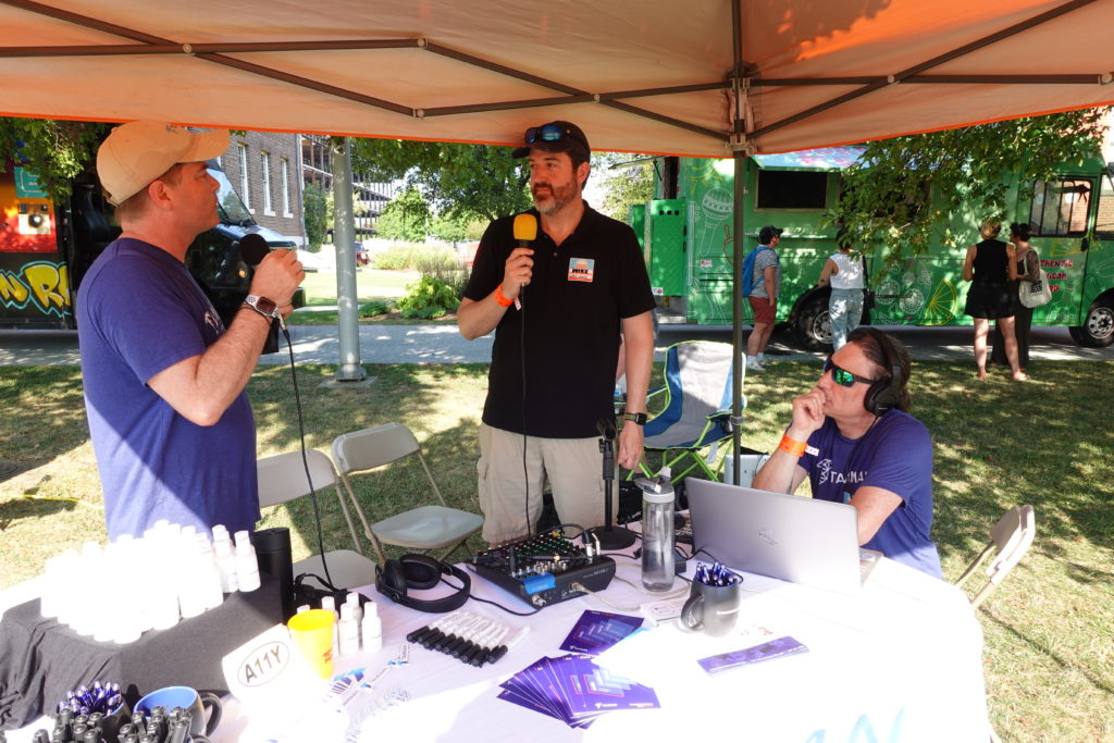 Marty Molloy and Mike Mangos kick off the podcast while Marcus works his mixing magic at a table loaded with Tamman t-shirts, pens, mugs, bug spray, and sunscreen for attendees. 