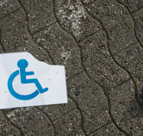 A torn and wet disabled person sign on the ground.