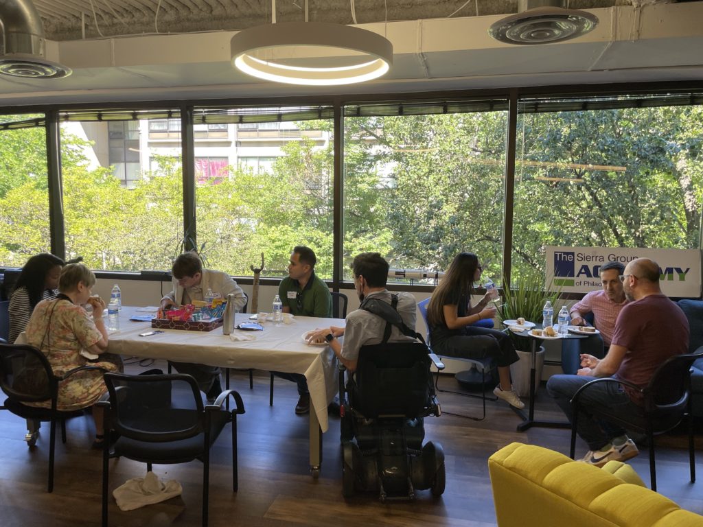 A diverse group of attendees sit around tables enjoying a quick meal before the next session begins.