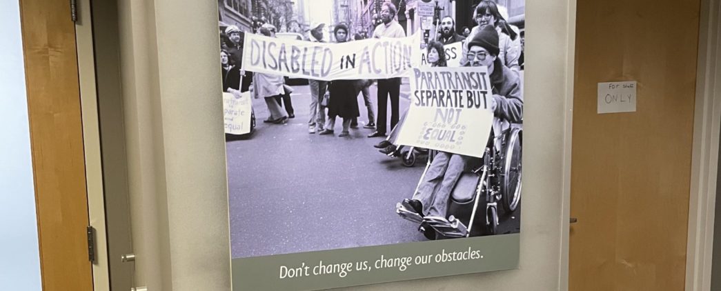 A poster showing people with disabilities protesting, with the following quote underneath. "Don't change us, change our obstacles."