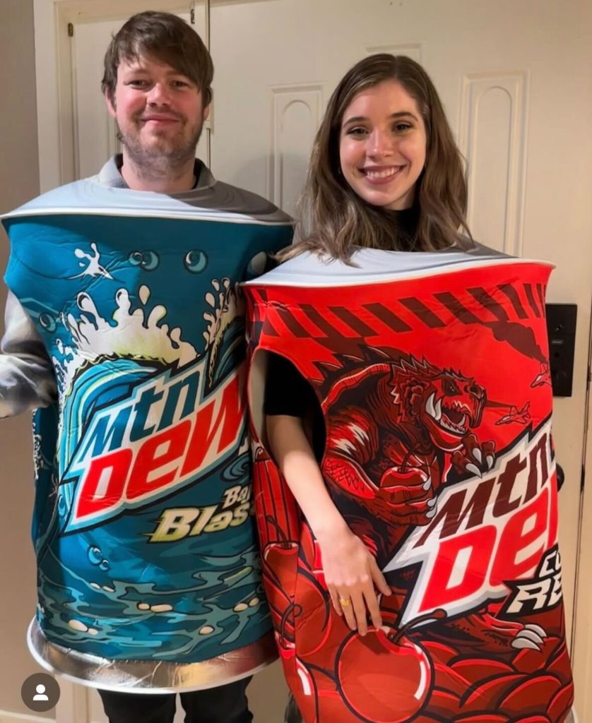 Collin is wearing a giant Mountain Dew Baja Blast can. Natalee is wearing a giant Mountain Dew Code Red can.