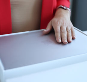 A woman opens a box containing an Apple MacBook Air.