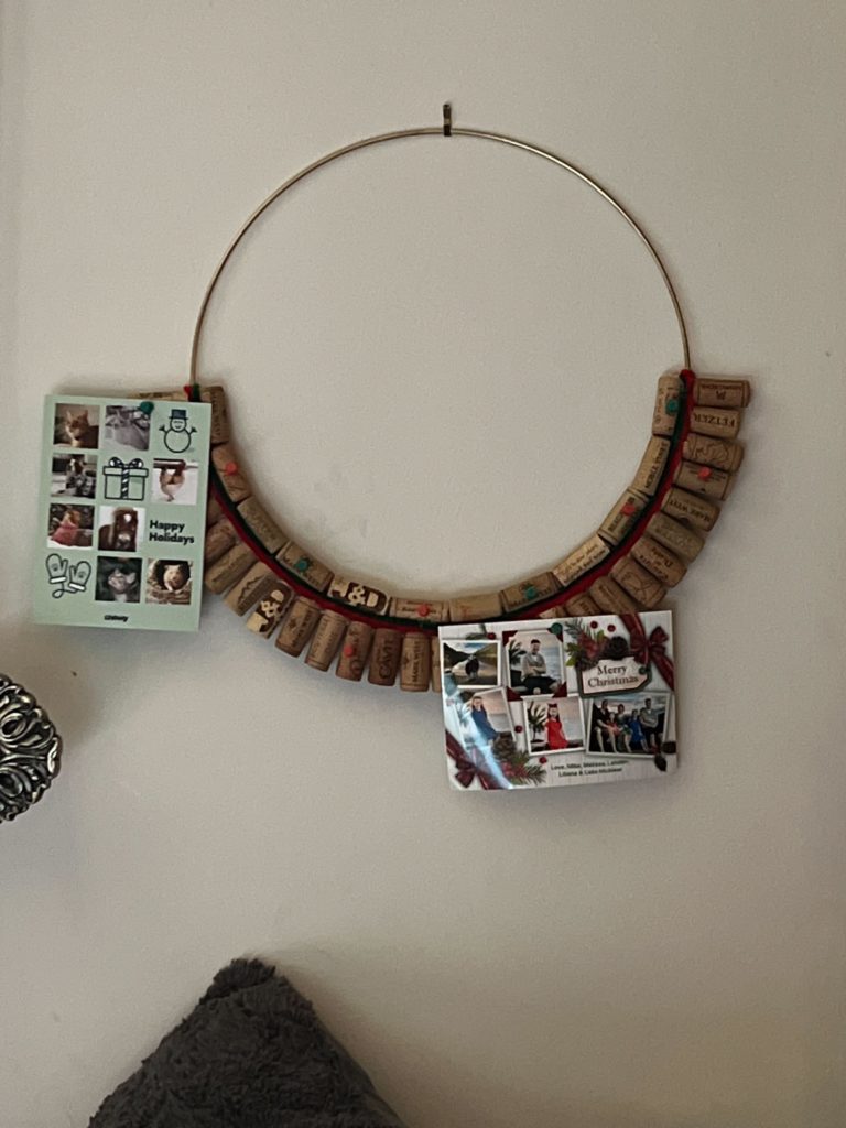 A hand-made holiday card holder made up of wine corks around a golden hoop.