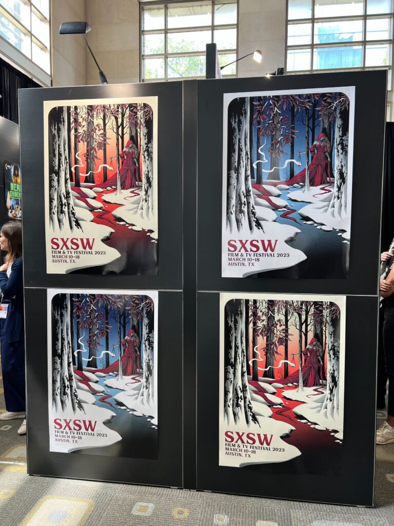 4 printed posters of a woman in a long red cloak walking through a snowy forest and over a creek. The trees have berries on them. There are two versions of the four posters: two have a red backdrop, and two have a blue backdrop.